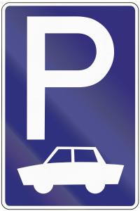 a road sign with a car parked under a large p at Hostel Florenc in Prague