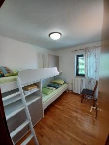a bedroom with a bunk bed and a chair at Apartments Katarina in Vantačići