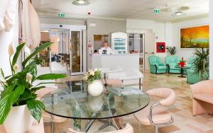 a lobby with a glass table and pink chairs at Hotel Baltic in Gabicce Mare