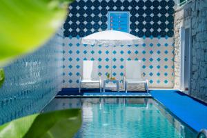 a swimming pool with two chairs and a blue and white wall at DAM HOTEL LARA in Antalya