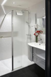 a white bathroom with a shower and a sink at Logis Le Prieuré in Locronan