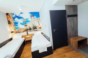 a room with two beds and a wall with a painting at blue hotel in Kalisz