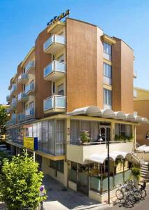 a tall building with balconies and tables on the side of it at Hotel Acerboli in Rimini