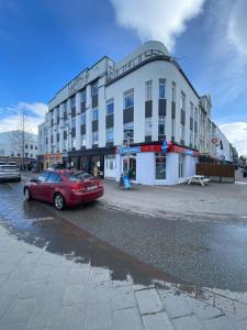a red car parked in front of a building at Day Dream Townhall Square Apartments in Akureyri