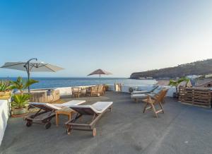 eine Terrasse mit Stühlen und Tischen und Meerblick in der Unterkunft Beach Apartment in Playa de Santiago