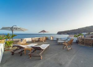 Un patio con sillas y mesas y vista al mar. en Beach Apartment, en Playa de Santiago
