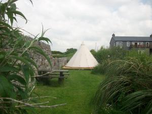 ein großes weißes Zelt in einem Hof mit einer Bank in der Unterkunft Aille River Tourist Hostel Glamping Doolin in Doolin