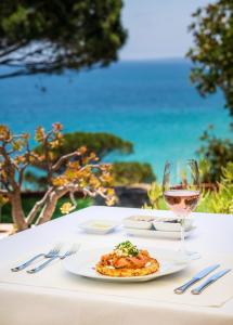 a table with a plate of food and a glass of wine at Boutique Hotel Vivenda Miranda in Lagos