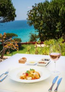a table with a plate of food and a glass of wine at Boutique Hotel Vivenda Miranda in Lagos