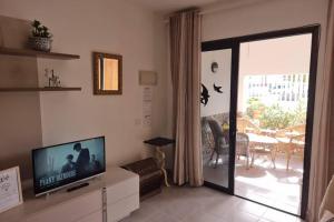 a living room with a tv and a sliding glass door at Casa Gales: Relax next to the Sea Apartment for Families in Corralejo
