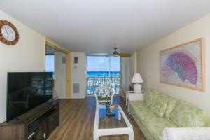 a living room with a couch and a tv at Spacious One Bedroom Harbor View Condos at Ilikai Marina With Private Balcony in Honolulu