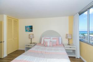 a bedroom with a bed with two lamps and a window at Spacious One Bedroom Harbor View Condos at Ilikai Marina With Private Balcony in Honolulu