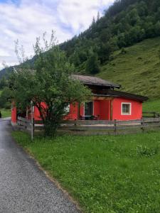 una casa roja al lado de una colina en Elto Wagau en Fusch an der Glocknerstraße