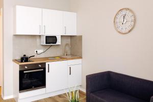 eine Küche mit weißen Schränken und einer Uhr an der Wand in der Unterkunft Apartment an der Altstadt: #Oslo in Hameln