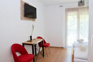 a living room with red chairs and a table and a tv at Prenoćište Slapovi in Jajce