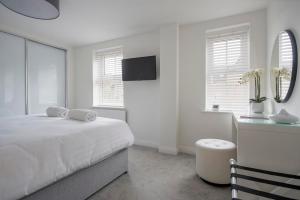 a white bedroom with a bed and a table and a mirror at Penleys Apartment in York