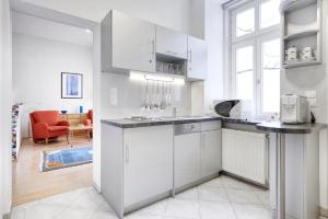 Apartments Deutschmeister في فيينا: مطبخ مع دواليب بيضاء وغرفة معيشة