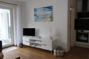 ein Wohnzimmer mit einem TV und einem weißen Schrank in der Unterkunft Ferienwohnung Strandblick, Ferienanlage "Blaumuschel" in Lubmin