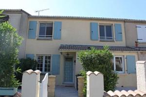 dom z niebieskimi okiennicami i białym płotem w obiekcie Holiday Home With Pool In Marseillan w mieście Marseillan