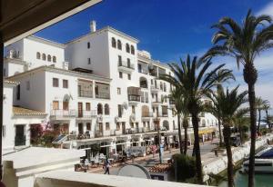 a large white building with palm trees next to a street at El Patio de Doña Julia in Bahia de Casares