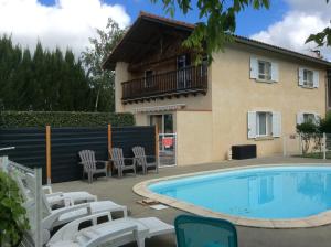 a house and a swimming pool with chairs and a house at GÎTE EN COMMINGES in Franquevielle