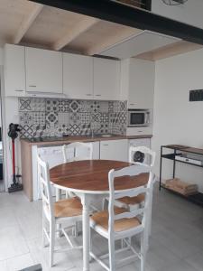 - une cuisine avec une table en bois et des chaises blanches dans l'établissement Maisonette 200m de la plage, à Saint-Jean-de-Monts