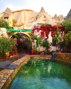 ギョレメにあるRoc Of Cappadociaの花の水のプールと建物