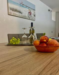 a bowl of fruit on a table with wine bottles and grapes at La Primavera in Anacapri