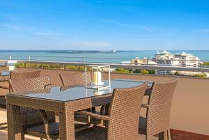 una mesa y sillas en un balcón con vistas al océano en Ramada Suites by Wyndham Zen Quarter Darwin en Darwin