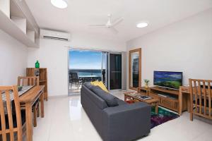 Ramada Suites by Wyndham Zen Quarter Darwin في داروين: غرفة معيشة بها أريكة وتلفزيون وطاولة