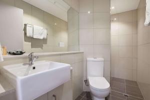 La salle de bains blanche est pourvue d'un lavabo et de toilettes. dans l'établissement Ramada Suites by Wyndham Zen Quarter Darwin, à Darwin
