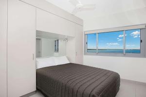 Ramada Suites by Wyndham Zen Quarter Darwin في داروين: غرفة نوم بسرير ونافذة كبيرة