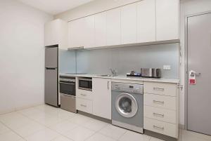 a kitchen with a sink, microwave, and refrigerator at Ramada Suites by Wyndham Zen Quarter Darwin in Darwin