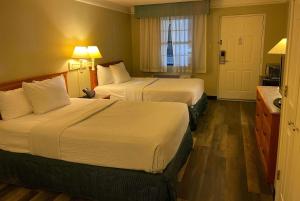 a hotel room with two beds and a window at Travelodge by Wyndham Tuscaloosa in Tuscaloosa