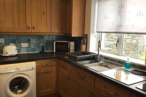 een keuken met een wastafel en een wasmachine bij Crofters Cottage at 100 Midtown in Melness