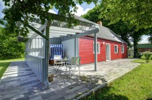- un abri rouge avec une table et des chaises sur la terrasse dans l'établissement fewo1846 - Rotes Haus - idyllisch gelegenes Haus mit 2 Schlafzimmern und großem Grundstück, à Husby