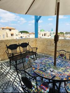 a patio with two tables and chairs and an umbrella at Jasmine House in ‘Akko