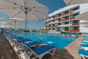 a swimming pool with chairs and umbrellas next to a building at Lucky Residence in Zatoka