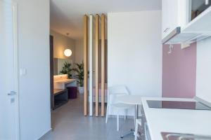 een keuken met witte werkbladen en een tafel en stoelen bij Gelli Apartments in Kos-stad