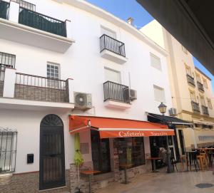 biały budynek z pomarańczową markizą na ulicy w obiekcie Apartamentos MareaBeach w mieście Torremolinos