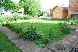 a garden with a lawn with plants and a house at Apartmani ,studija i sobe Savić in Soko Banja