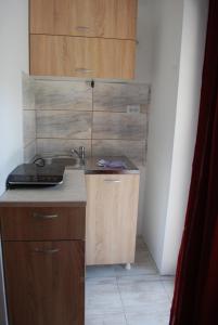 a small kitchen with a sink and wooden cabinets at Apartmani ,studija i sobe Savić in Soko Banja