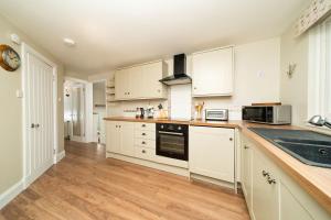 uma cozinha com armários brancos e piso em madeira em FerryView em Broughty Ferry