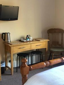 a wooden desk with two chairs and a television on a wall at Auplands en-suite Rooms in Lymington
