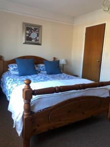 um quarto com uma grande cama de madeira com almofadas azuis em Auplands en-suite Rooms em Lymington