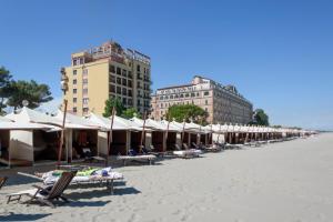 una fila de sombrillas y sillas en una playa en Appartamento Calmo 3DX, en Lido de Venecia