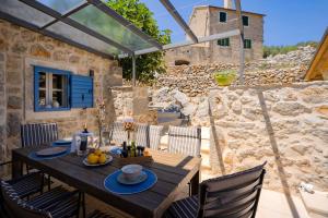 a wooden table and chairs on a patio with a stone wall at Villa Zanino in Veliko Grablje