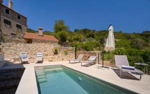 a pool with chairs and an umbrella next to a building at Villa Zanino in Veliko Grablje