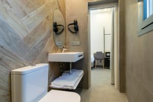 ein Badezimmer mit einem Waschbecken, einem WC und einem Spiegel in der Unterkunft Real Maqueda - Málaga in Málaga