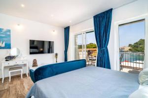 a bedroom with a blue bed and a balcony at Corallium Blue in Pomena